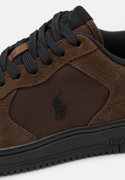 Bruine sneaker met een combinatie van suède en mesh materialen, zwarte veters, textuurpanelen en een logoaccent. Rubberen zool.