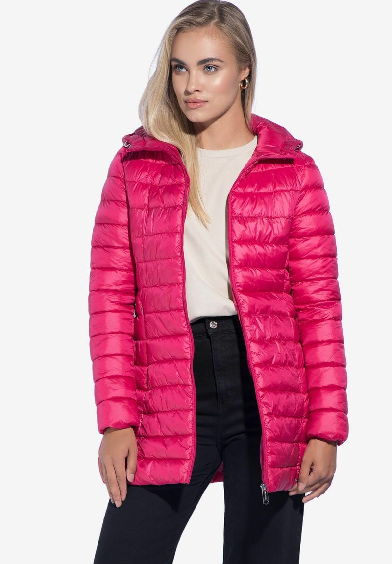 Fuchsia Pufferjacke mit horizontaler Steppung, abnehmbarer Kapuze, vorderem Reißverschluss und Taschen, getragen über einem leichten Oberteil und schwarzen Hosen.