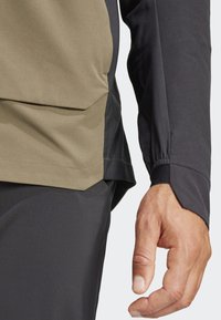 Langermige shirt in kaki en zwart, met een gemêleerde stof, elastische manchetten en een zijspleet voor meer bewegingsvrijheid.