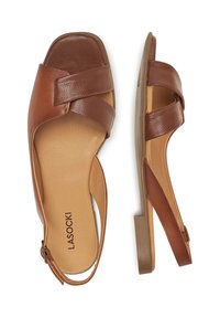 Sandalias de cuero marrón con correas cruzadas y un tacón bajo. La plantilla es de un color marrón claro, con un logotipo de la marca en negro.