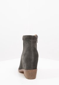 Schwarze Wildleder-Ankle Boots mit leicht geschwungenem Absatz, Reißverschlussdetail auf der Rückseite und glatter Textur. Sauberes, minimalistisches Design.