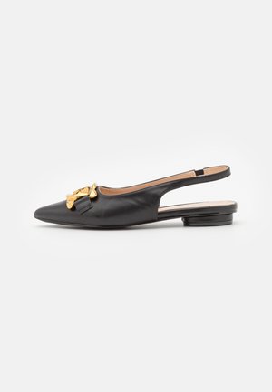 Chaussure plate en cuir noir à brides arrière avec un bout pointu, présentant un détail en chaîne dorée à l'avant et un petit talon rond.