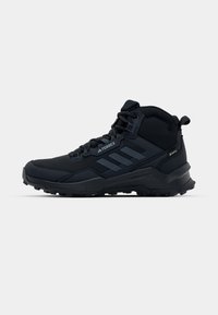Czarne buty trekkingowe o wysokiej cholewce, wykonane z syntetycznego materiału, z teksturowanymi akcentami i wytrzymałą podeszwą zapewniającą przyczepność.