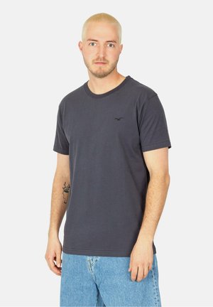 Graues T-Shirt mit kurzen Ärmeln aus Baumwollmischgewebe, mit rundem Ausschnitt und einem kleinen Logo-Akzent auf der Brust. Getragen mit hellblauen Jeans.