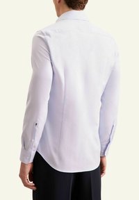 Camicia a maniche lunghe azzurro chiaro con colletto a punta, tessuto testurizzato e orlo stondato. Presenta polsini con bottoni e dettagli con logo.