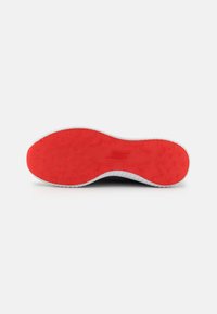 Schuhsohle mit einer strukturierten Oberfläche in leuchtendem Rot, umgeben von einem weißen Gummirahmen, der für Traktion und Flexibilität ausgelegt ist.