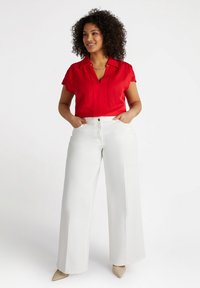 Camicia rossa a maniche corte con colletto, abbinata a pantaloni bianchi a gamba larga. L'outfit presenta una texture liscia e dettagli sottili sulla camicia.