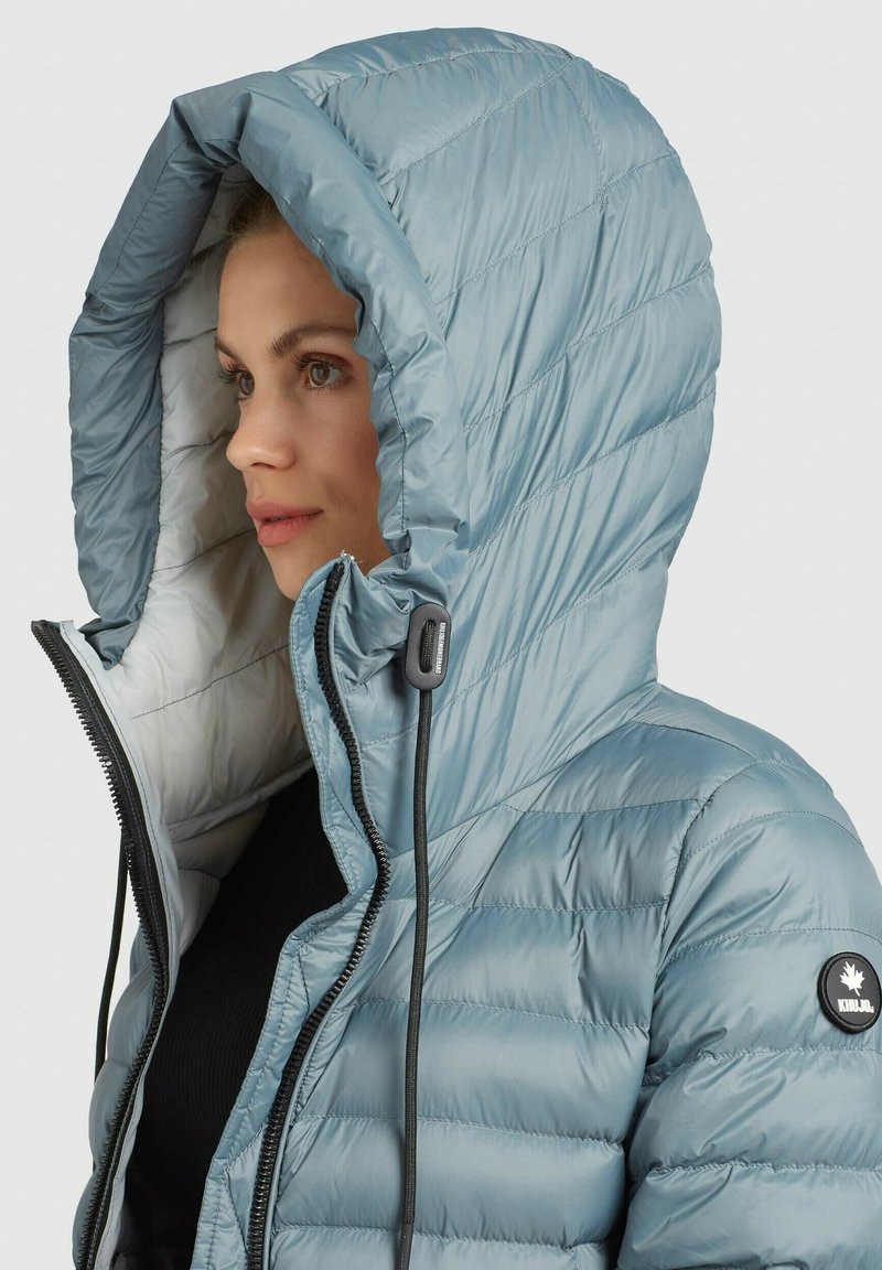 Helles blaues Puffer-Jacke mit einer großen Kapuze, gesteppter Optik und schwarzen Akzenten. Verfügt über einen Reißverschluss vorne und verstellbare Kordeln.