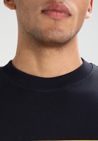 Sudadera azul marino con cuello redondo y cuello de canalé, que presenta una textura suave y un diseño ajustado en el cuello.