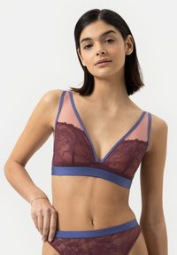 Bralette mit tiefem V-Ausschnitt aus burgunderfarbener Spitze, ausgestattet mit einem transparenten Einsatz und breiten blauen Trägern. Glatter Bund mit blauen Akzenten.