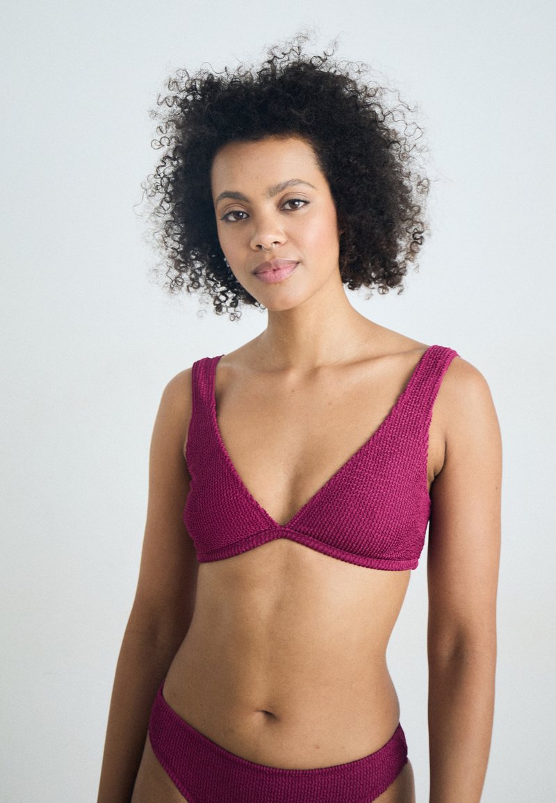 Strikket bikini-sett i dyp magenta; har en V-hals topp med brede stropper og matchende underdeler, teksturert stoff og minimalistisk design.
