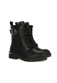 Botas de cuero negro hasta el tobillo con puntera redonda, cordones delanteros y detalles en metal dorado. Tienen un tacón cuadrado y una asa de bucle.
