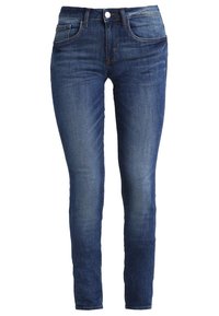 Jeans de mezclilla azul ajustados con un lavado desgastado, cinco bolsillos, trabillas para cinturón y cierre frontales de botón. Textura suave y diseño de pierna recta.
