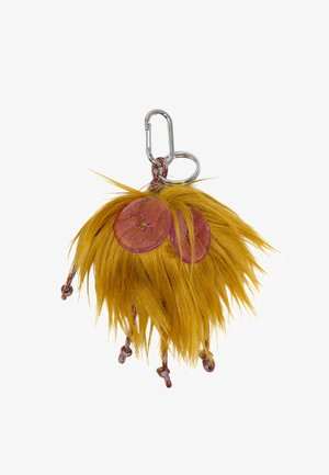Puszysty, żółty breloczek z dwoma okrągłymi, przezroczystymi różowymi dyskami; zawiera srebrny karabińczyk i teksturowane włókna.