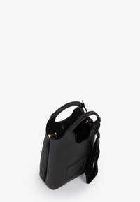 Borsa a tracolla in pelle nera texture, con due manici, apertura superiore con chiusure a scatto e accessorio in pelle attaccato, mostrata su sfondo bianco.