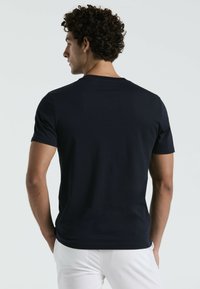 Marineblauwe T-shirt met korte mouwen van gladde katoen, voorzien van een ronde hals en een aansluitend design, gedragen met witte broek.