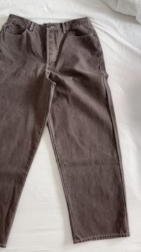 Pantaloni in cotone marroni con una vestibilità rilassata, cinque tasche e dettagli in cucitura bianca. Il tessuto ha una finitura morbida e leggermente testurizzata.