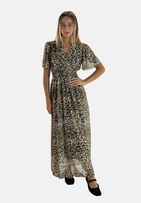 Robe maxi avec un motif léopard, en tissu léger, manches courtes et taille élastiquée. Associée à des chaussures Mary Jane noires.