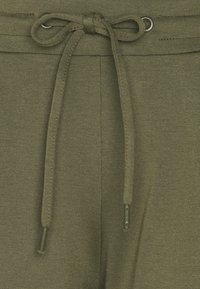 Olivgröna sweatpants med dragsko i midjan och metallöglor, mjuk texturerad tyg och en strömlinjeformad passform.