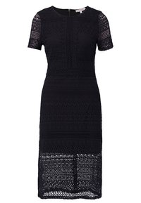 Robe noire arrivant au genou avec manches courtes, motifs complexes en dentelle sur toute la surface, encolure ronde avec fermeture éclair au dos.