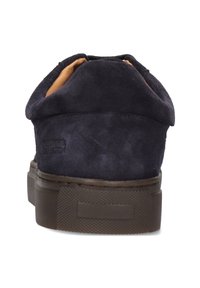 Dunkelblaue Wildledersneaker mit einer kontrastierenden braunen Gummisohle, gepolstertem Kragen und minimalistischem Branding an der Ferse. Rückansicht dargestellt.