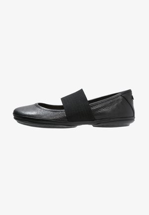Ballerines en cuir noir avec un bout arrondi, une sangle élastique sur le cou-de-pied et une semelle flexible. Texture lisse avec un minimalisme dans le design.