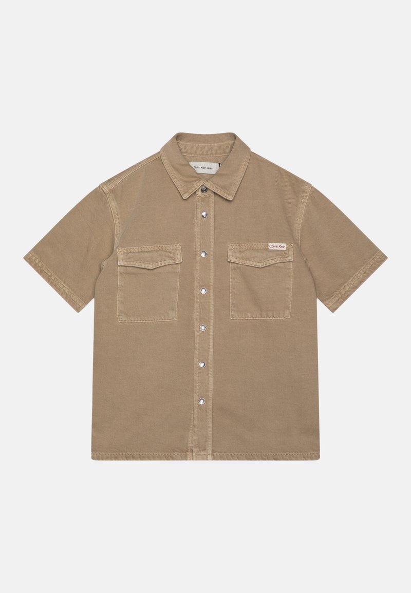 Κοντομάνικο, ανοιχτό καφέ πουκάμισο με κουμπιά φτιαγμένο από μαλακό ύφασμα, που διαθέτει δύο τσέπες στο στήθος και γιακά. Ασημένια κουμπιά με κούμπωμα.
