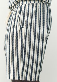 Shorts rayés avec un motif blanc et marine, en tissu texturé, avec des poches latérales et une taille élastique.