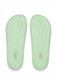 Semelles moulées vertes avec surface texturée, présentant des motifs en losanges et un badge logo central. Matériau souple et flexible pour le confort.