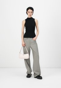 Svart, ribbet ermeløs topp, lysegrå vide bukser og en liten rosa håndveske. Outfiten har elegante linjer og kontrasterende farger.