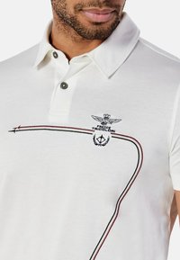 Polo shirt bianco in cotone, con patta a due bottoni, logo ricamato e righe colorate in rosso e verde sul davanti.