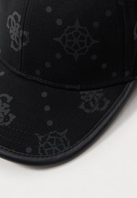 Boné preto com um tecido texturizado, com um padrão de logótipos e pontos discretos, e uma aba curva.