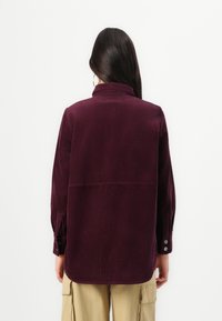 Bordeaux corduroy shirt met een kraag, lange mouwen en knoopmanchetten. Heeft een verticale ribbelstructuur en een recht gesneden zoom.