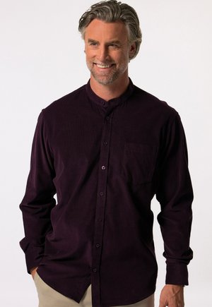 Camisa de botonadura en un suave tejido de color púrpura oscuro, con cuello tipo mao, mangas largas y un único bolsillo en el pecho.