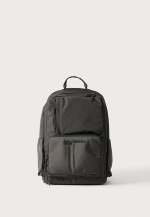 Sac à dos rectangulaire noir avec plusieurs compartiments zippés et une poignée supérieure, avec le logo embossé "Karl Lagerfeld Jeans" sur la poche avant.