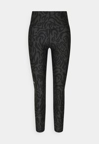 Leggings neri a vita alta con un motivo astratto di stampa animale scuro e un piccolo logo bianco Under Armour sulla coscia sinistra.