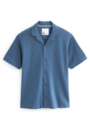 Chemise bleue à manches courtes avec boutons, col camp et étiquette de marque à l'intérieur du col sur fond blanc.