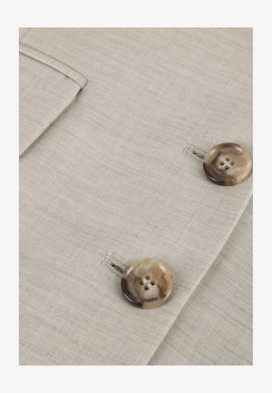 Lys grått stoff med en teksturert overflate har to runde, marmoriserte knapper, hver med fire hull, og en sidelomme.