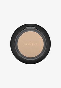Kompaktfoundation i en rund behållare. Har ett genomskinligt lock med svart kant. Slät ljusbeige puder inuti, med "FOREO" präglat.