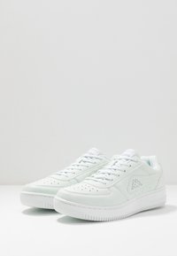 Weiße Leder-Sneaker mit durchlässiger Zehenpartie, Schnürdesign, gepolsterter Ferse und hellblauen Akzenten. Dicke weiße Gummisohle.