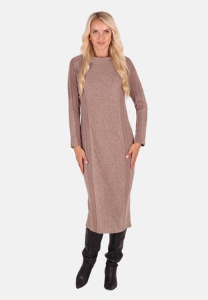 Long, beige dress with a textured pattern, featuring long sleeves and a straight silhouette, paired with black knee-high boots.