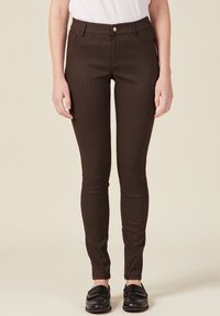 Pantalones skinny marrón a cuadros con una textura suave, que cuentan con un cierre frontal de botón y cinco bolsillos, combinados con mocasines negros.