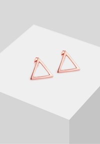Paire de boucles d'oreilles clous triangulaires à monture ouverte en or rose présentées sur une surface blanche inclinée.