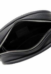 Borsa in pelle nera con finitura testurizzata, chiusura a zip e tasca interna. Forma morbida con bordi lisci e rivestimento a contrasto.