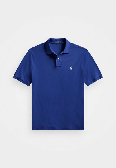 Modra polo majica iz gladkega materiala, z klasičnim ovratnikom, kratkimi rokavi in majhnim rumenim izvezenim logotipom na levem prsnem delu.