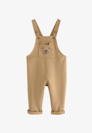 Salopette color beige realizzata in tessuto morbido con spalline regolabili, caratterizzata da una tasca a forma di faccia d'orsa e con risvolti sui pantaloni.