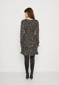 Vestido preto floral com mangas longas, corpete franzido e saia em camadas. Apresenta uma bainha com babados e padrões florais decorativos em tons de amarelo e azul.