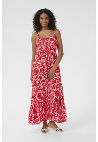 Robe maxi florale rouge et blanche avec des bretelles fines, un corsage ajusté et des fentes latérales. Fabriquée en tissu léger, elle présente une silhouette fluide.