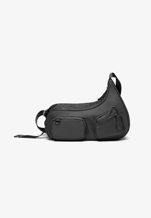 Sort slingtaske med glat materiale, buet form, to lynlåslommer foran, justerbar rem og ingen synlig hardware.