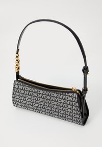 Μαύρη και λευκή τσάντα χε�ιρός με γεωμετρικό μοτίβο, διαθέτει χρυσό φερμουάρ, λεπτό λουρί ώμου και κομψές λεπτομέρειες με λογότυπο DKNY.